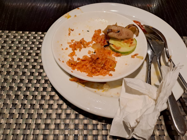 在餐厅的餐桌上摆放有盘子剩菜和金属器皿的空盘子图片下载