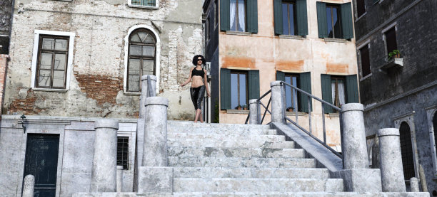 一个美丽的女人站在威尼斯风格的桥的楼梯顶端。图片下载