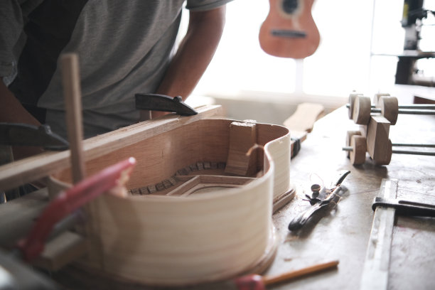 一名男子正在用夹子固定工作台上的四弦琴图片下载