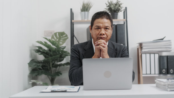 使用手提电脑，穿着正装的亚洲资深男性商人，自信的专业簿记员，律师，股票交易员或经纪人。图片下载