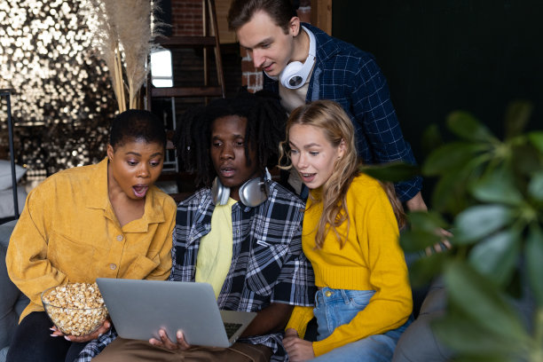 各种各样的大学生，朋友，年轻人一起在笔记本电脑上看电影或电影院，玩得开心，吃着爆米花。国际友谊理念，休闲时光，居家活动图片下载