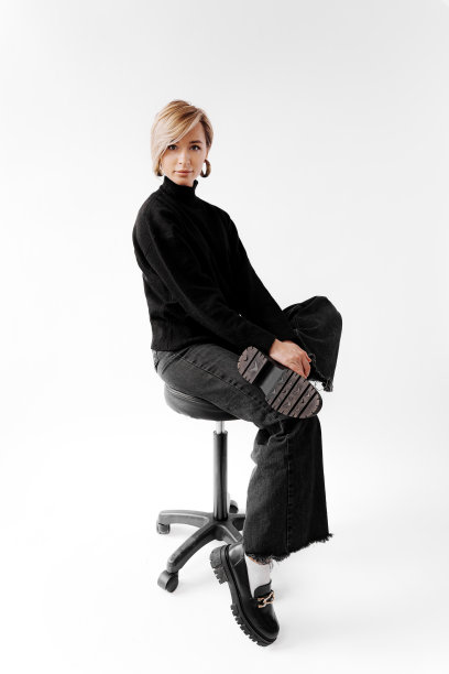 穿着黑色连衣裙的时髦女人坐在椅子上图片下载