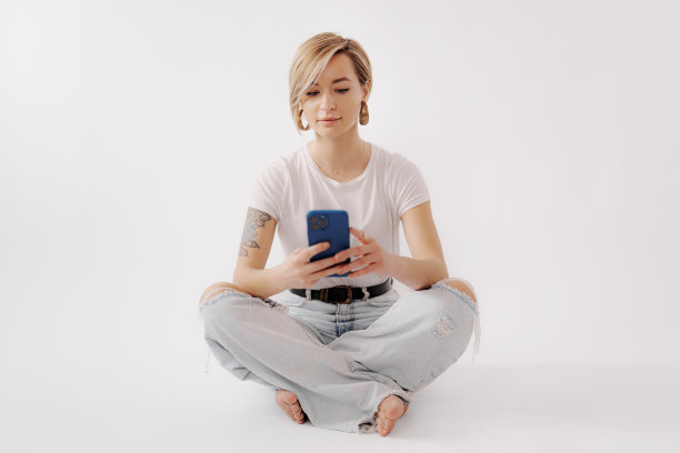 女人坐在地板上玩智能手机图片下载