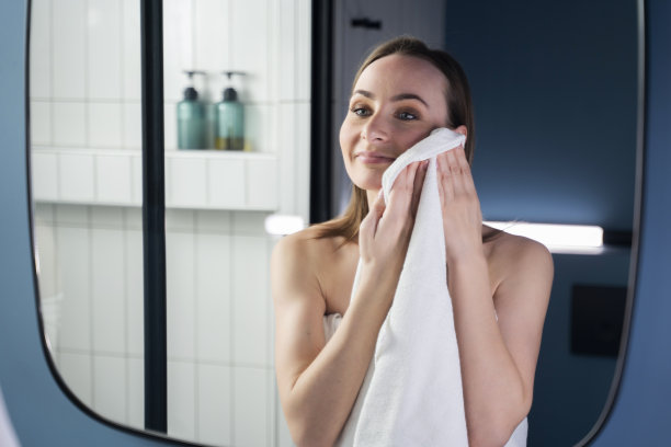 面部皮肤护理。一个漂亮的女人在一个现代化的浴室里洗完澡用毛巾擦干净的脸。早晨身体护理程序的概念。图片下载