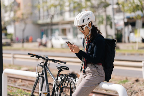 亚洲女性在好天气骑自行车上班。她休息时用手机图片下载