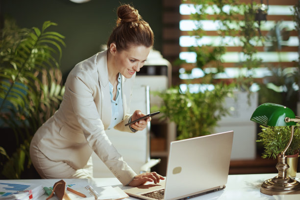 微笑的女员工在绿色办公室使用智能手机应用程序图片下载