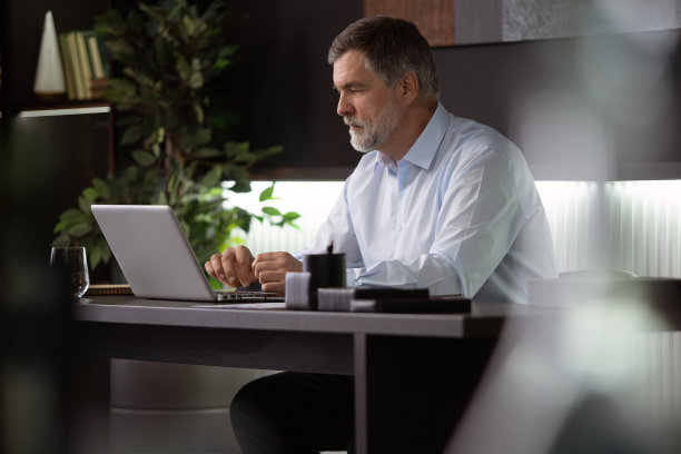 商人在办公室使用笔记本电脑。快乐成熟的男人，企业家，小企业主在网上工作。图片下载