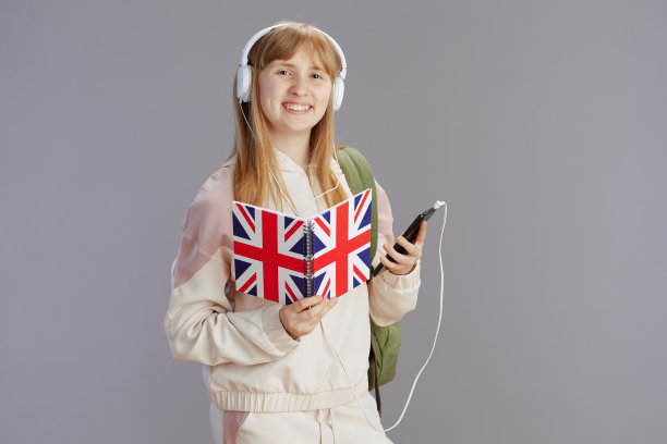 穿着米色运动服微笑的时髦女学生正在使用智能手机图片下载