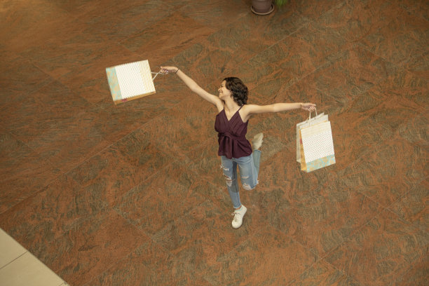 拿着购物袋的女人在购物中心玩得很开心图片下载