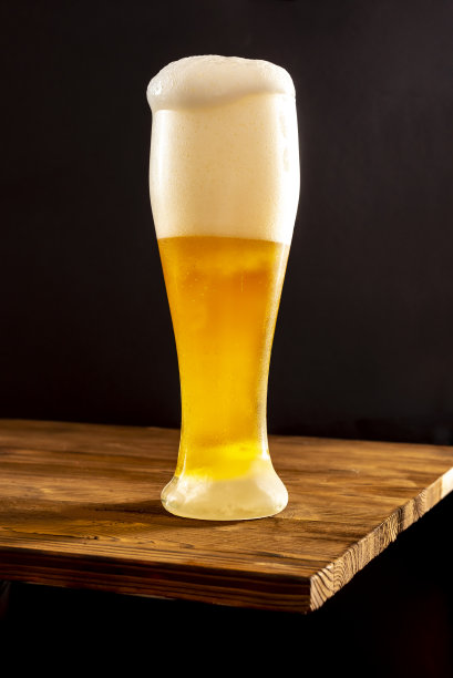 木桌上，雾气蒙蒙的玻璃杯里盛着淡啤酒。图片下载