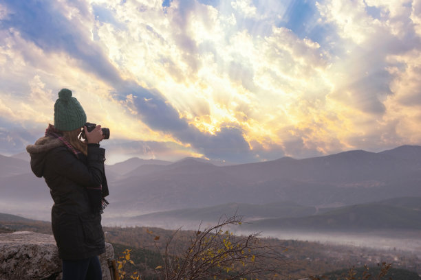 美丽的女孩用她的专业相机在山地风景中拍照图片下载