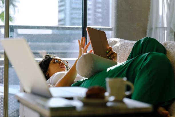 一位现代秘鲁妇女在家里沙发上使用数字平板电脑的侧面照片图片下载