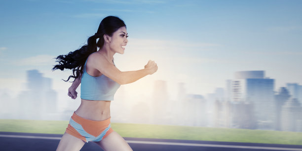 美丽的年轻女子在模糊的城市背景下奔跑图片下载