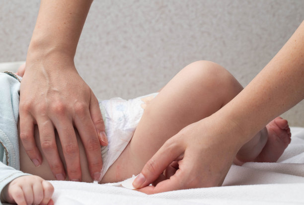 母亲系好扣子，给婴儿换尿布，特写。文本复制空间图片下载