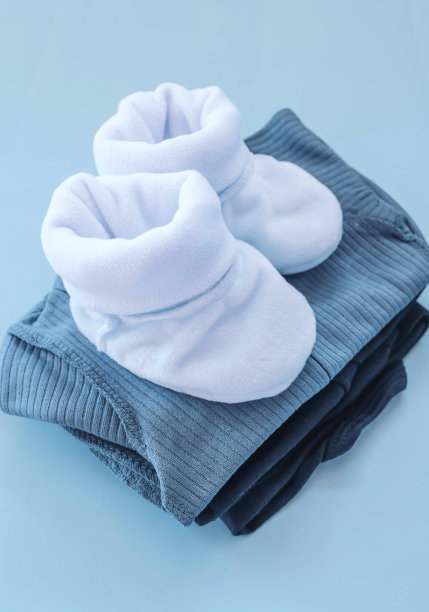 一个新生男孩的衣服堆在蓝色背景上。靴子，工装裤，西装图片下载