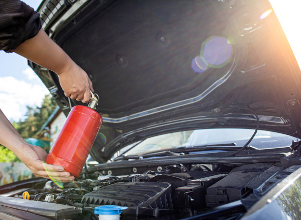 汽车司机将粉末灭火器对准着火和冒烟的汽车发动机舱。汽车起火，背景。电气短路图片下载