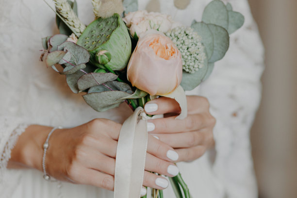 美丽的新娘手持漂亮的花束准备婚礼。新娘手捧鲜花在室内。广告照片。庆祝活动的概念图片下载