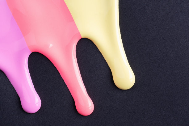 彩虹色的液体滴在黑色的纸上流淌。抽象艺术。五颜六色的油漆滴在黑色的墙上图片下载