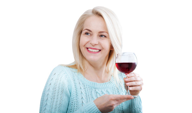 一个快乐的女人端着一杯红酒，看起来很放松地走过镜头。图片下载