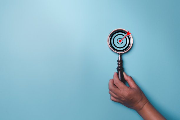 手持目标板内的老式放大镜聚焦业务目标在蓝色背景和复制空间。搜索，目标，策略，成功。成功的营销策略目标图片下载