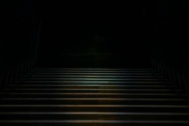 一段宽阔的金属镶边楼梯通向阴暗的黑暗图片下载