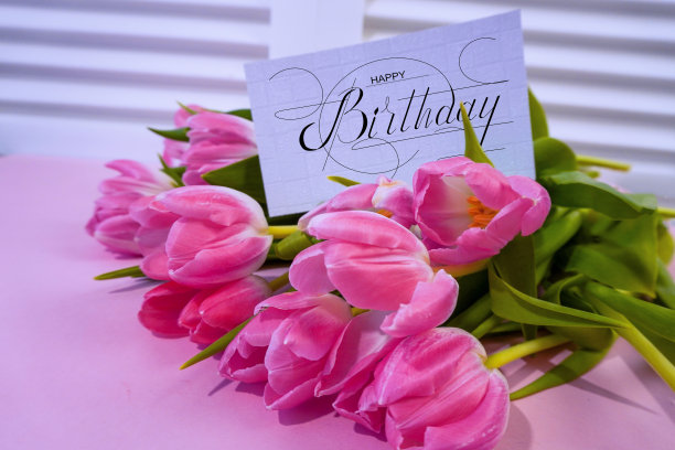 明信片上，网上挂着生日祝福的横幅，上面写着生日快乐的题词，一束鲜花上写着祝贺的字条图片下载