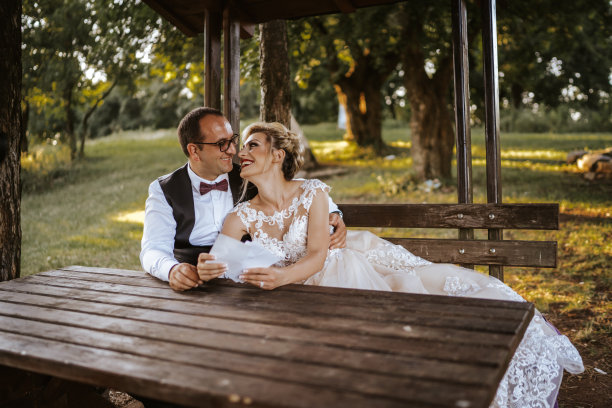 浪漫婚礼：情侣坐在自然木制凉亭的长椅上图片下载