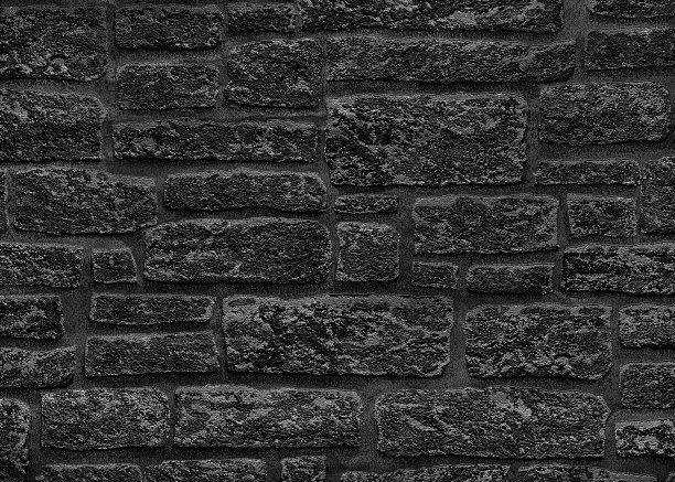 黑色的砖墙上有灰色的斑点。粗糙的深色墙壁的纹理。图片下载