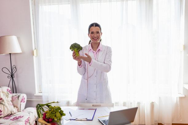 女营养学家拿着西兰花站在诊所里图片下载