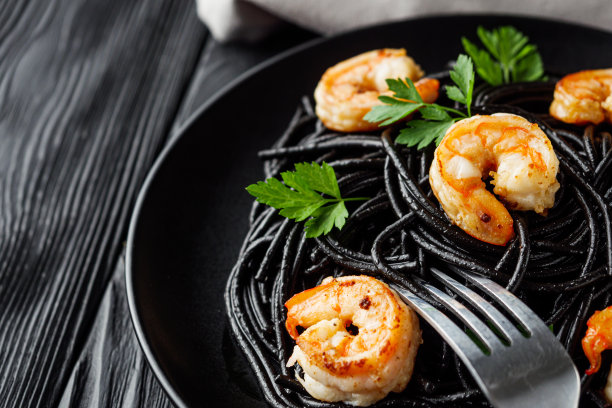 美味的黑色意大利面，黑色质朴的木制背景图片下载