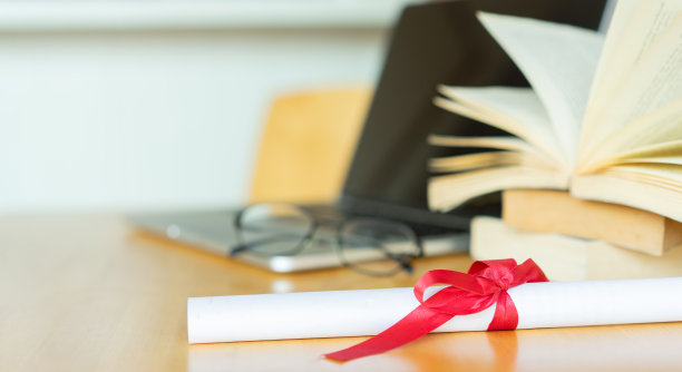 将学士学位证书在笔记本电脑上与图书馆的书合在一起，用于在线学习毕业概念图片下载