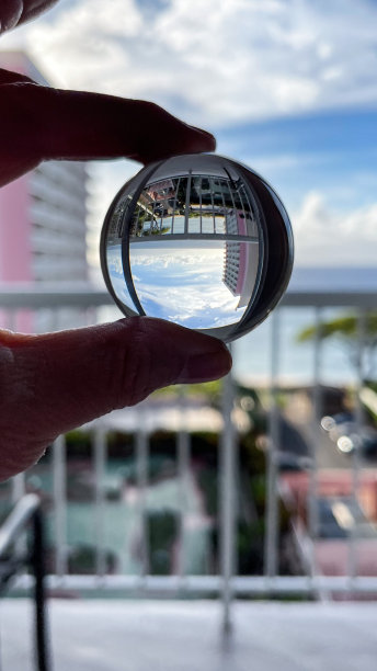 一个女人手里拿着水晶球，映出毛伊岛粉色度假胜地的倒影图片下载