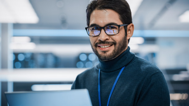 一个才华横溢的拉丁人的特写肖像，看着镜头，迷人地微笑。工作中的西班牙裔商人，信息技术经理，专业软件开发人员。图片下载