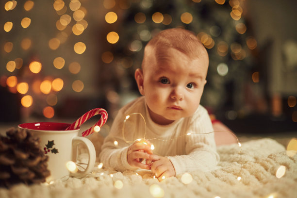 地板上摆满了花环。可爱的小婴儿在家。新年装饰。假期的概念图片下载