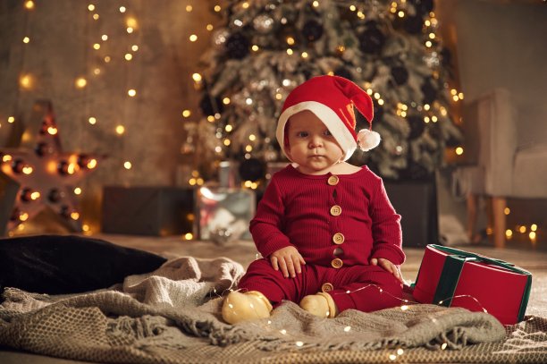穿着节日服装，戴着圣诞帽。可爱的小婴儿在家。新年装饰。假期的概念图片下载