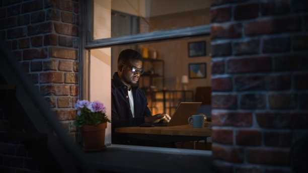 晚上在家用笔记本电脑工作的黑人富有成效的年轻人的肖像。网络安全专家检查启动网站协议从远程使用互联网。资讯科技专家图片下载