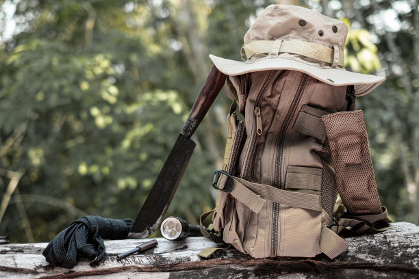 生存装备水桶帽背包远足刀露营手电筒搁在木制木材的背景是一片森林图片下载