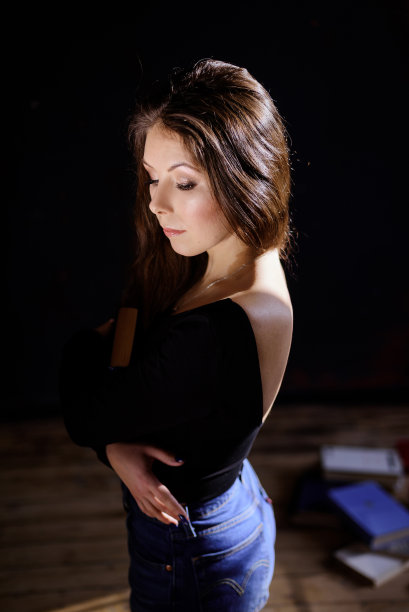 一个放松的女人坐在满屋子的书里看书图片下载