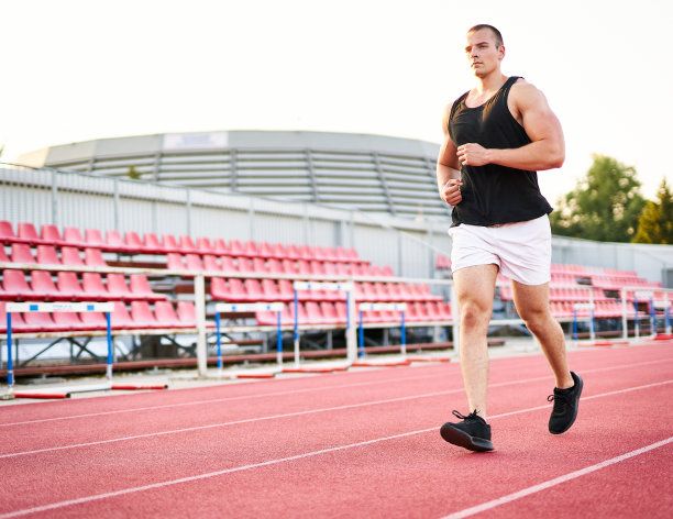 年轻肌肉健壮的男性短跑运动员在红色跑道上跑步-与千禧一代跑步者的健身和健康概念-照片左侧的Copyspace图片下载