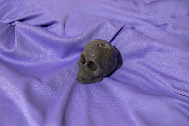 在紫色材料上用蜡制成的骷髅头。图片下载