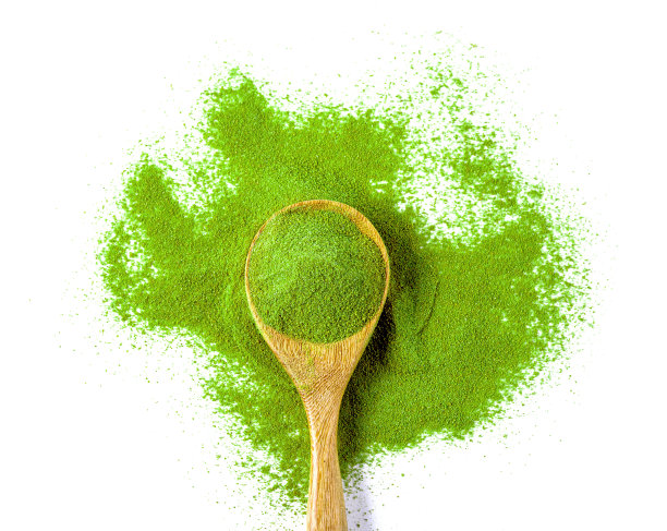 木勺与粉末绿茶隔离在白色背景。木勺与粉末抹茶绿茶隔离在白色背景。木勺上有抹茶绿色粉末，孤立在白色上图片下载