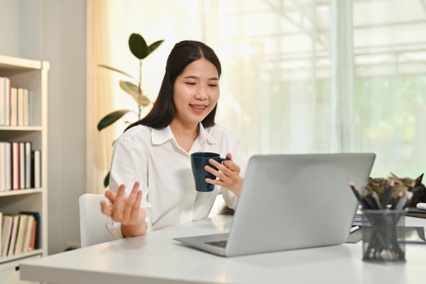 千禧一代的亚洲女性在家庭办公室的白色办公桌上使用笔记本电脑。技术，自由职业者和远程工作理念。图片下载