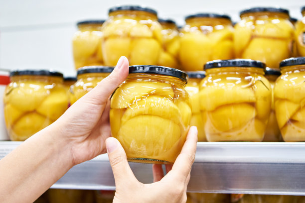 罐头桃子在玻璃罐中，在商店的手图片下载