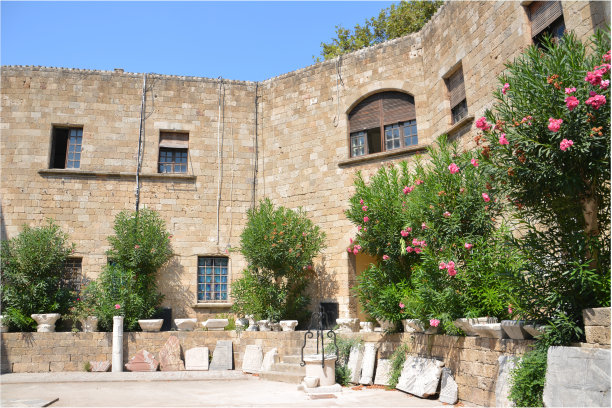 古城堡中的庭院，拱形窗户和前景中的绿树图片下载