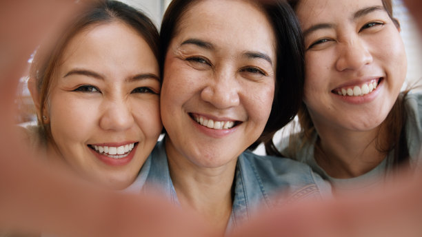 享受美好的温暖时光母亲节两个长大的孩子孩子女孩看着相机快乐拥抱拥抱做心形爱的手势给成熟的妈妈。亚洲中年妈妈青壮年三人笑笑脸图片下载