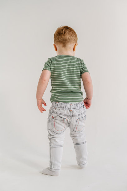 可爱的蹒跚学步的男孩站在家里玩耍，在白色背景的工作室里玩得很开心，复制空间。孩子玩。小孩子站在阳光充足的房间地板上。特写镜头。放文字的地方。图片下载