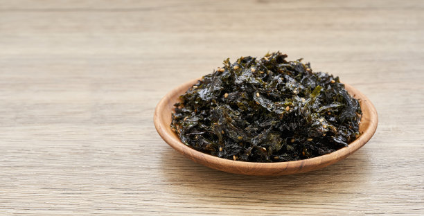 烤海苔和芝麻浇头在木桌背景上的木板。金，紫菜，紫菜图片下载