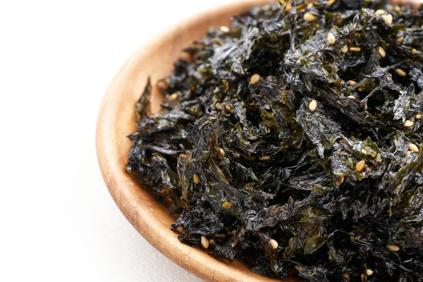 近景:烤海苔和芝麻点缀在白色背景的木板上。金，紫菜，紫菜图片下载