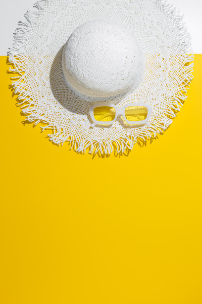 黄色背景上的白色太阳帽和黄色眼镜。暑假，夏日休闲概念，极简潮流平铺，两色照片俯视图宽边帽和太阳镜图片下载