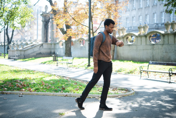 一个年轻的非洲裔美国人一边走一边看时间图片下载